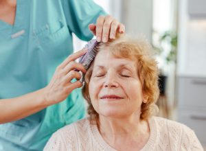 Smiling nurse brushes a senior woman's hair, showing care and compassion in a heartwarming moment of trust and support